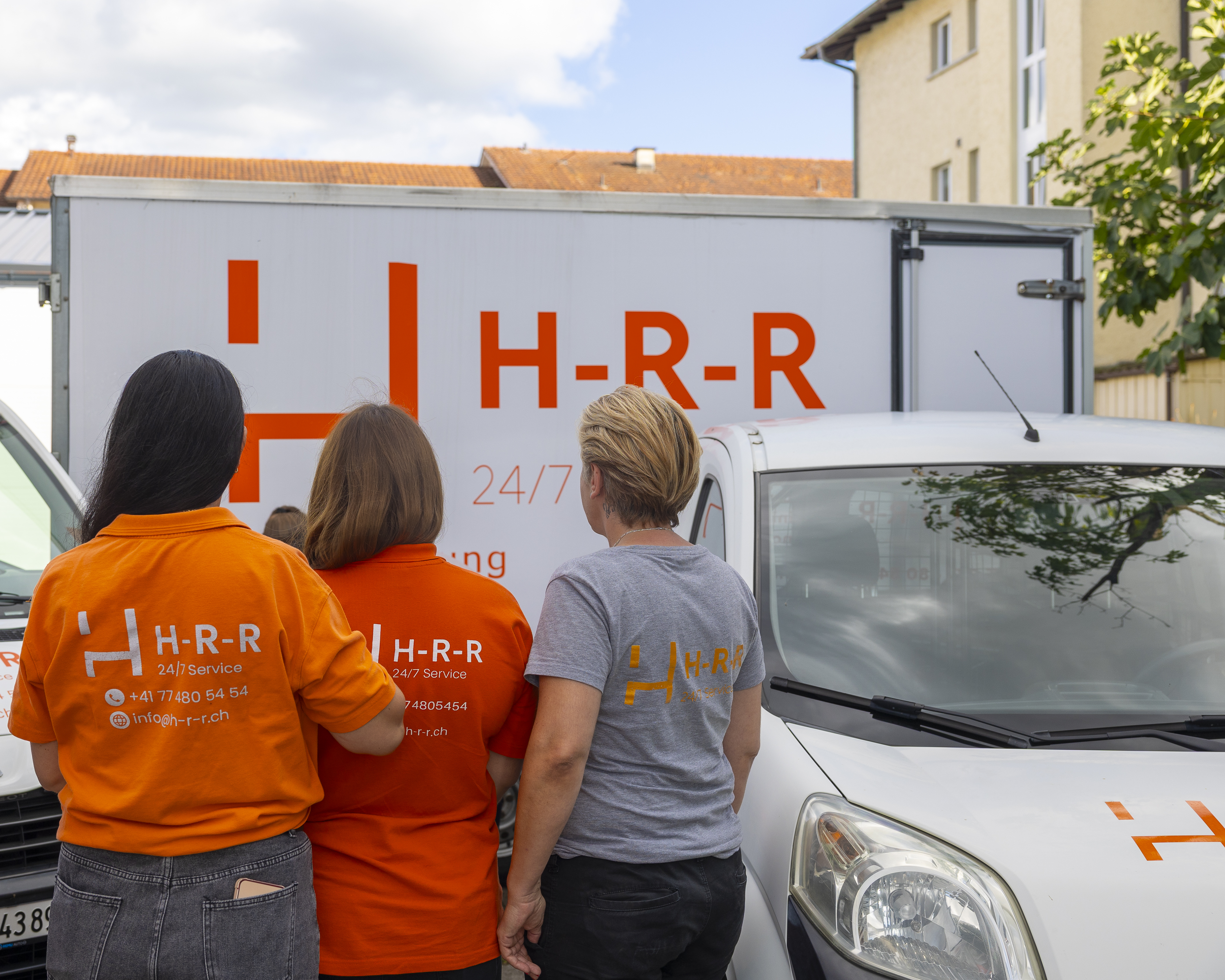 Mitarbeiterinnen vor den Firmenfahrzeugen der H-R-R Facility GmbH